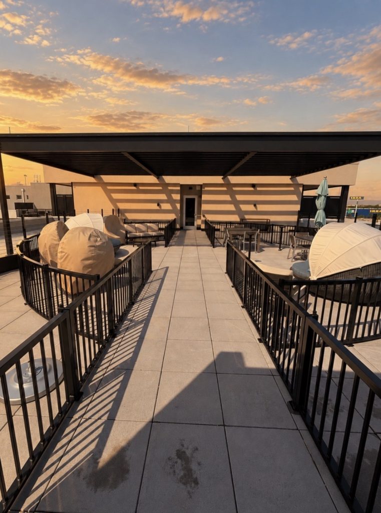Rooftop lounge walkway with metal railings at sunset